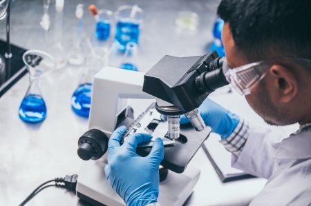 Health care researchers in a laboratory looking through a microscope